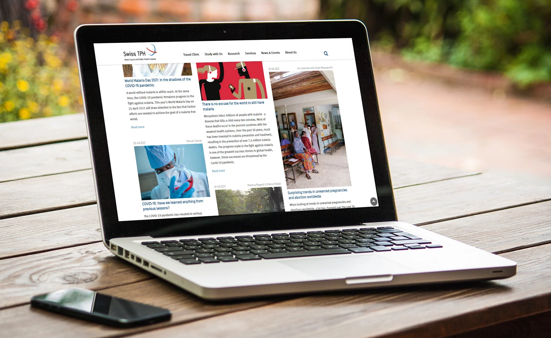 Laptop auf Tisch mit Smartphone daneben Umfassendes digitales Portal mit unzähligen Beiträgen News Berichten über individuelle Health Themen auf der TYPO3 Website für Swiss TPH entwickelt von CS2.