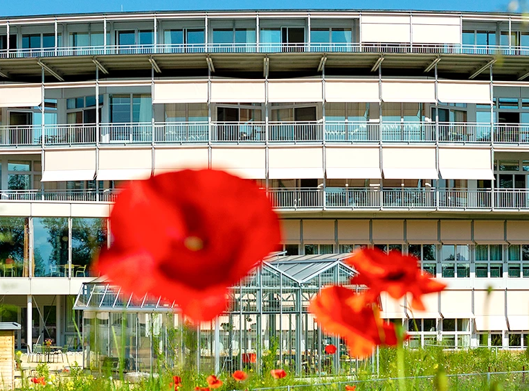 Fassadenansicht Gebäude SPZ in Nottwil am Sempachersee mit Mohnblume im Vordergrund