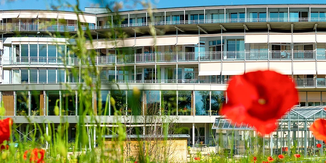 Fassadenansicht Gebäude SPZ in Nottwil am Sempachersee mit Mohnblume im Vordergrund