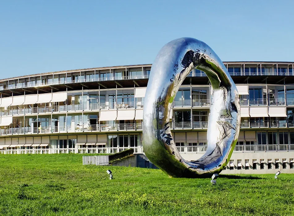 Stimmiges Bild zeigt das SPZ in Nottwil aus Seesicht mit Kunstwerk im Vordergrund welches im Park steht.
